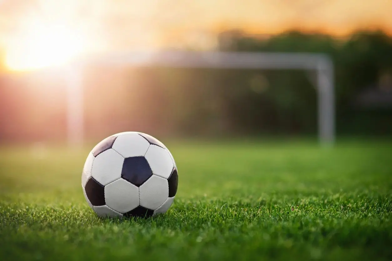 Soccer ball on field at sunset.